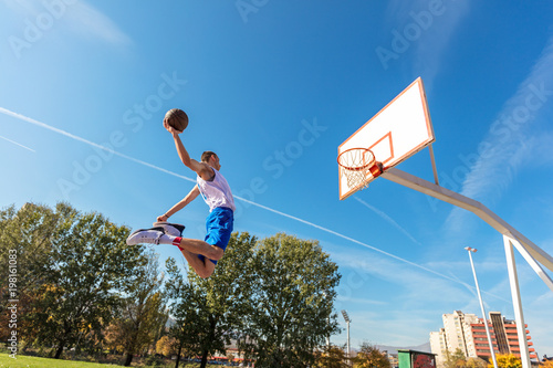 Young Basketball street player making slam dunk photo