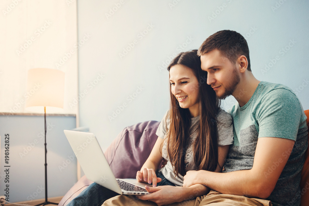 Young couple sitting at home and using laptop, surf the Internet. Young couple sitting at home and using laptop, surf the Internet.