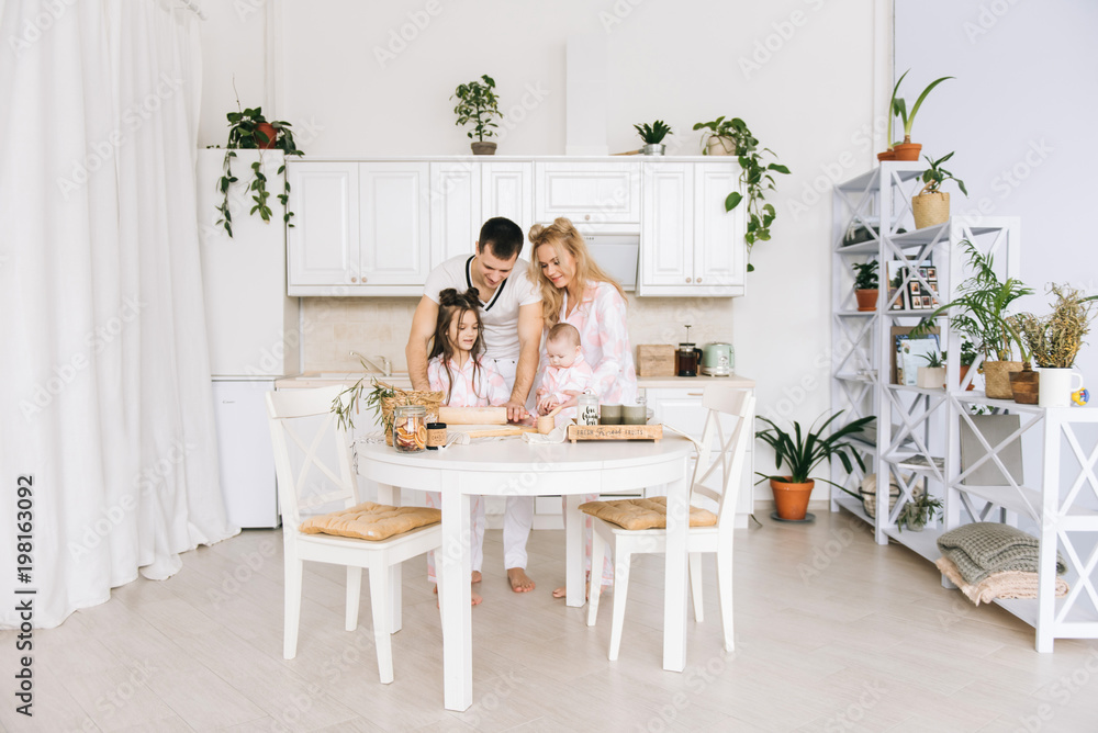 Happy loving family are preparing bakery together. Mother father and two daughter girl are cooking cookies and having fun in the kitchen. Homemade food and little helper. Happy loving family are preparing bakery together. Mother father and two daughter girl are cooking cookies and having fun in the kitchen. Homemade food and little helper.
