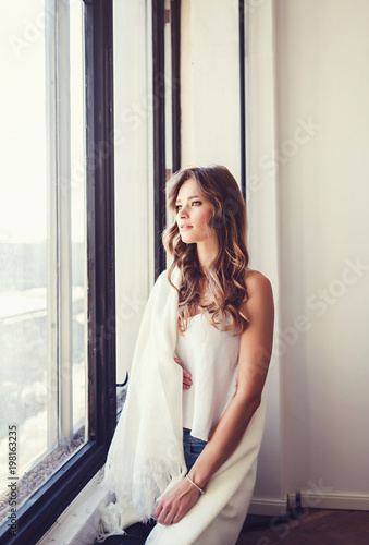 portrait of a calm and romantic woman after a window in the autumn time