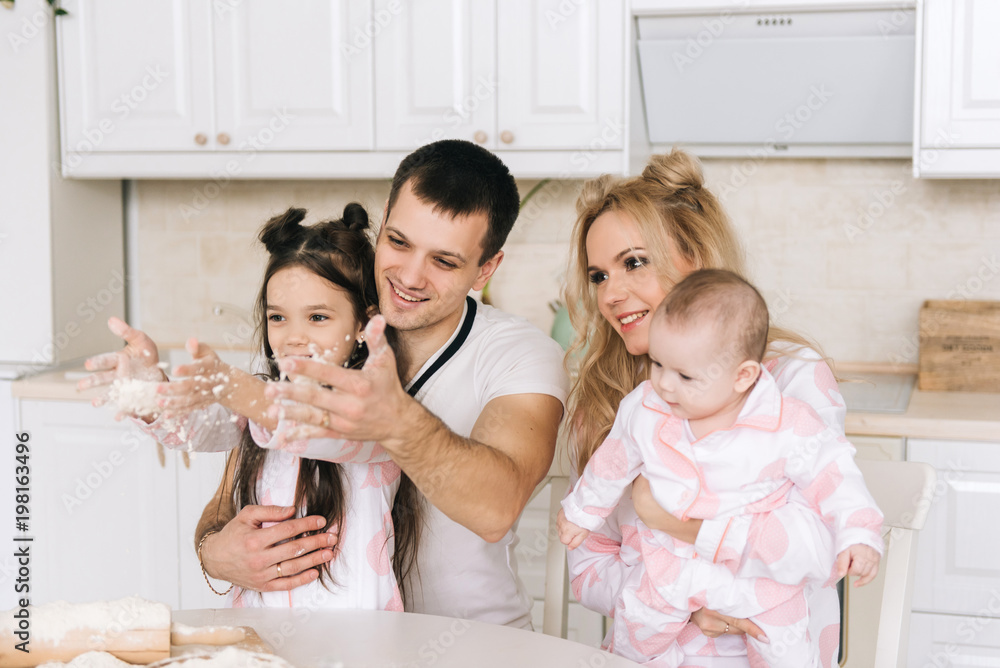 Happy loving family are preparing bakery together. Mother father and two daughter girl are cooking cookies and having fun in the kitchen. Homemade food and little helper. Happy loving family are preparing bakery together. Mother father and two daughter girl are cooking cookies and having fun in the kitchen. Homemade food and little helper.