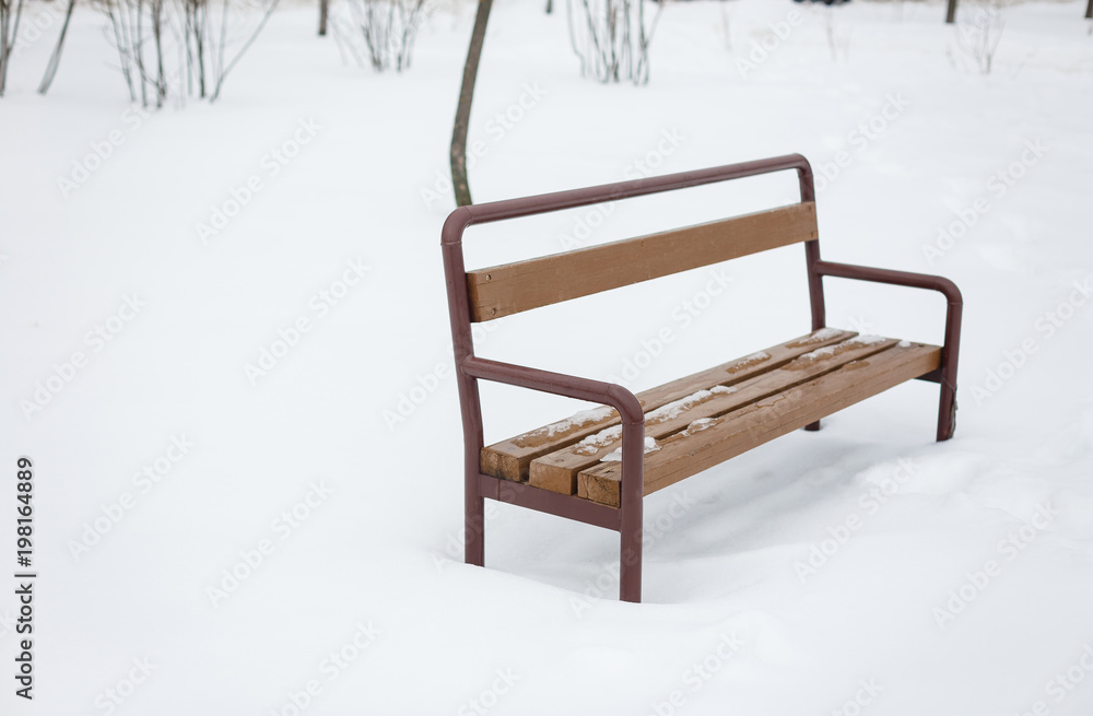 Iron shop, black with a wooden seat, stands in a winter park, in the snow