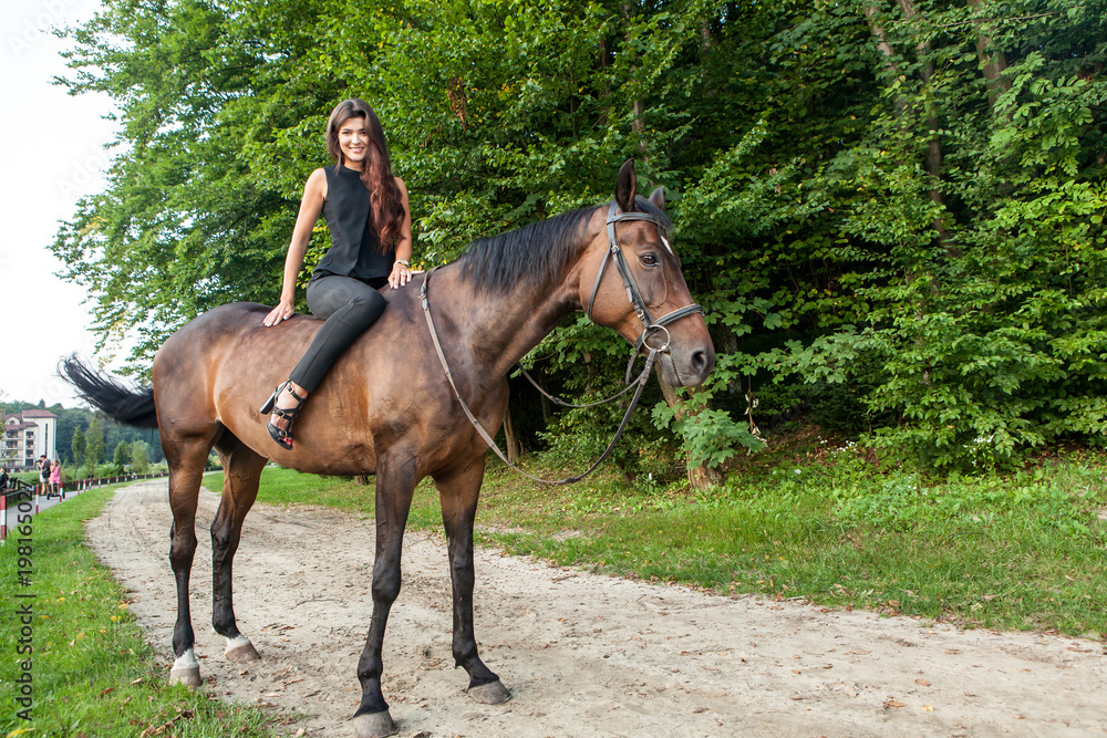 Pretty young woman riding a brown horse Pretty young woman riding a brown horse