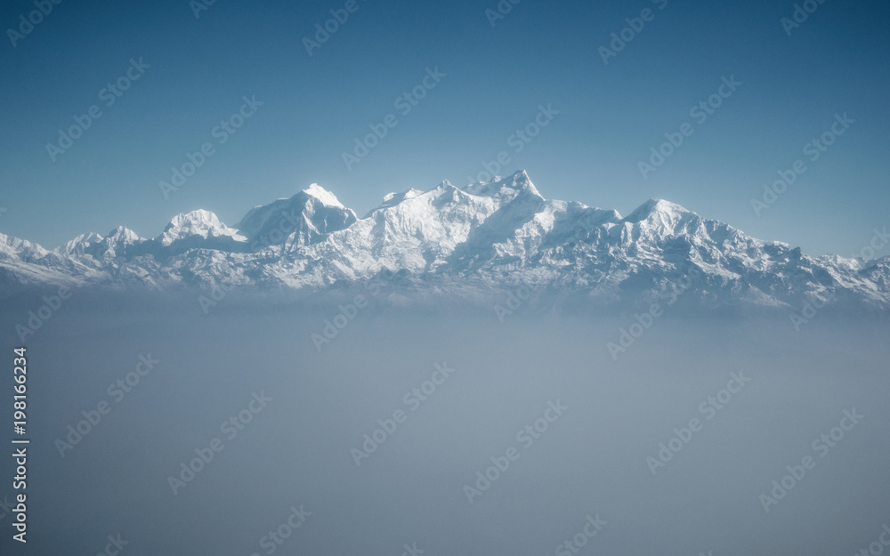 The Himalayas as seen from an airplane in Nepal. Layer of clouds beneath the mountain tops.
