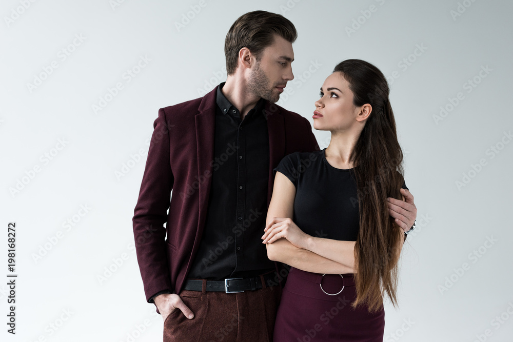 serious couple hugging and looking at each other, isolated on grey serious couple hugging and looking at each other, isolated on grey