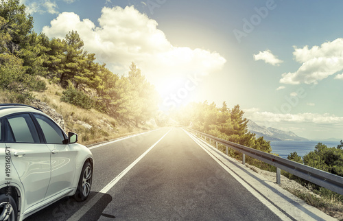 A white car rushing along a high-speed highway in the sun. © Denis Rozhnovsky