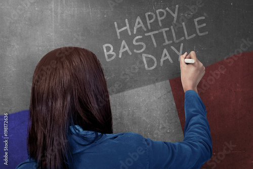 Rear view of woman writing happy bastille day on the wall