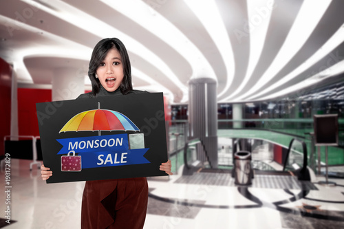 Happy asian woman holding board with Monsoon sale sign