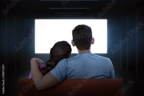 Portrait of asian couple sitting on couch watching blank tv
