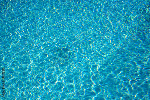 Textured light effect on the surface ripples of a blue outdoor swimming pool. Full frame background texture.