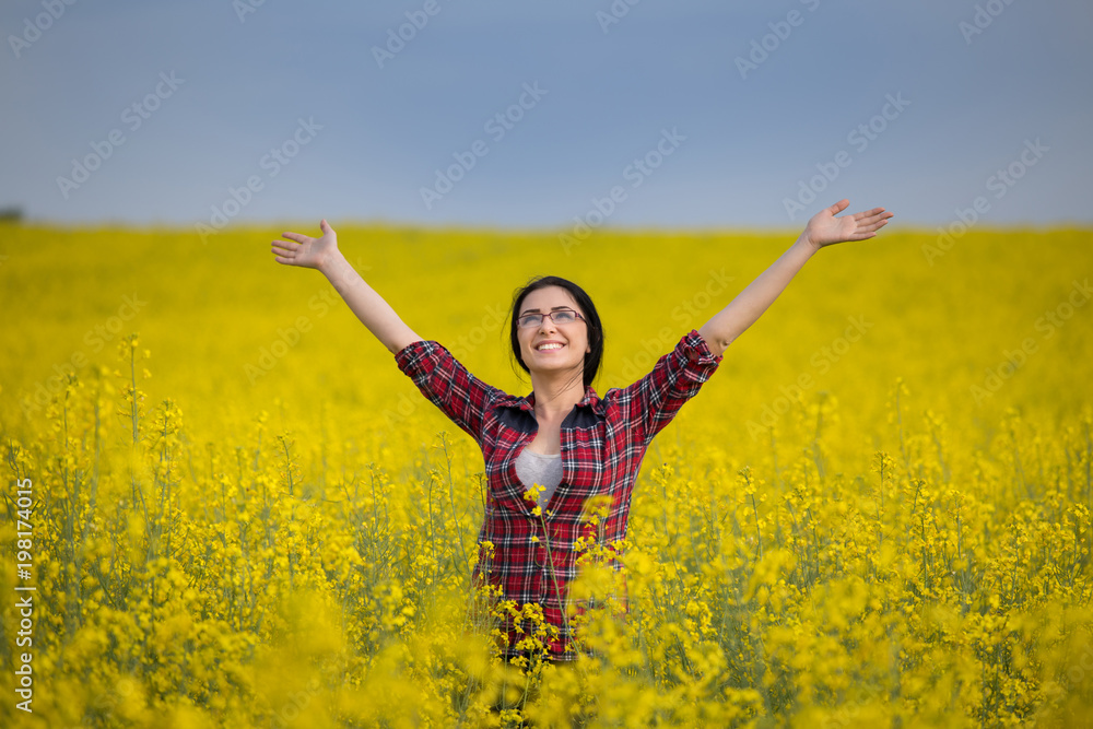 Girl with raised arms in yellow rapeseed field Girl with raised arms in yellow rapeseed field