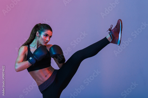 Obraz na plátně Photo of young sportswoman 20s in tracksuit and black boxing gloves fighting and