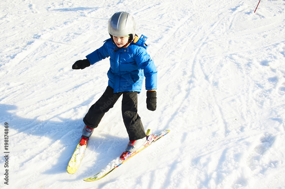 Child boy skiing in winter mountains. Active kid with safety helmet and goggles. Ski race for young children. Winter sport for family. Kids ski lesson in school. Young skier racing in snow