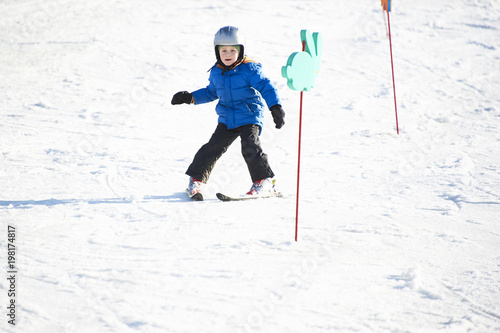 Child boy skiing in winter mountains. Active kid with safety helmet and goggles. Ski race for young children. Winter sport for family. Kids ski lesson in school. Young skier racing in snow