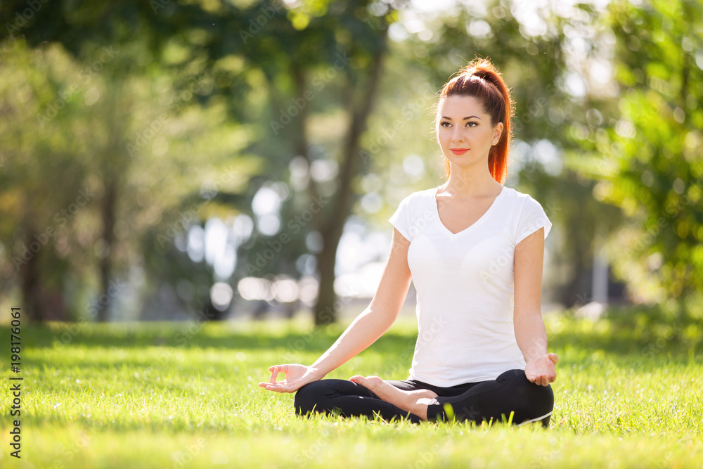Yoga outdoor. Happy woman doing yoga exercises, meditate in the park. Yoga meditation in nature. Concept of healthy lifestyle and relaxation. Pretty woman practicing yoga on the grass Yoga outdoor. Happy woman doing yoga exercises, meditate in the park. Yoga meditation in nature. Concept of healthy lifestyle and relaxation. Pretty woman practicing yoga on the grass