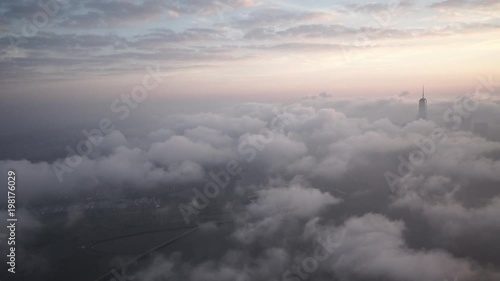 New York City sunrise aerial view approaching Manhattan's Financial District from over Ellis Island, while fog and low level clouds roll through.