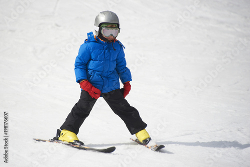 Child boy skiing in the mountains on snowy winter day. Kids in winter sport school in resort. Family fun in the snow. Skier learning and exercising on a slope.