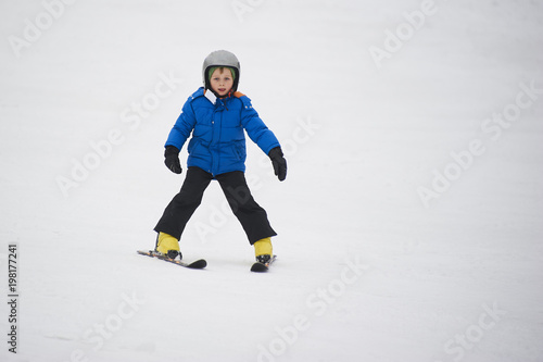 Child boy skiing in the mountains on snowy winter day. Kids in winter sport school in resort. Family fun in the snow. Skier learning and exercising on a slope.