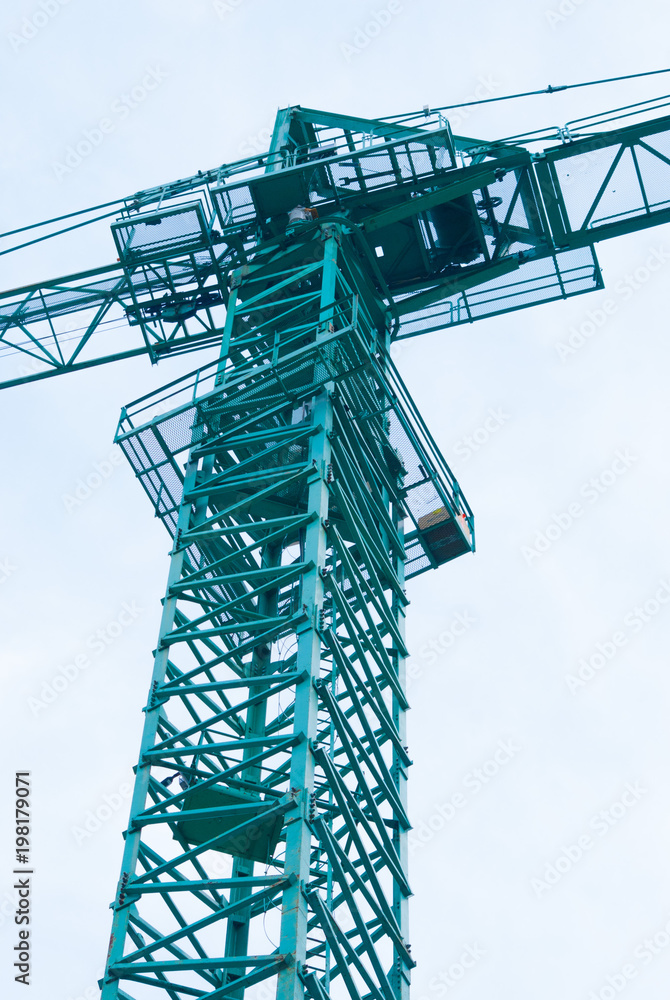 Cockpit photographed from the ground of a green crane in a construction site