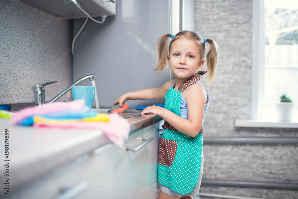 little girl washes dishes at home in the kitchen - obrazy, fototapety, plakaty 