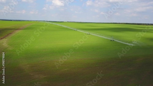 Modern automated irrigation equipment watering freshly seeded field. Irrigation of farmland to ensure the quality of the crop. Aerial view of internet connected irrigating machine in a wheat field photo