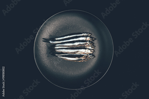 Top view of pile of fish in frying pan isolated on black photo