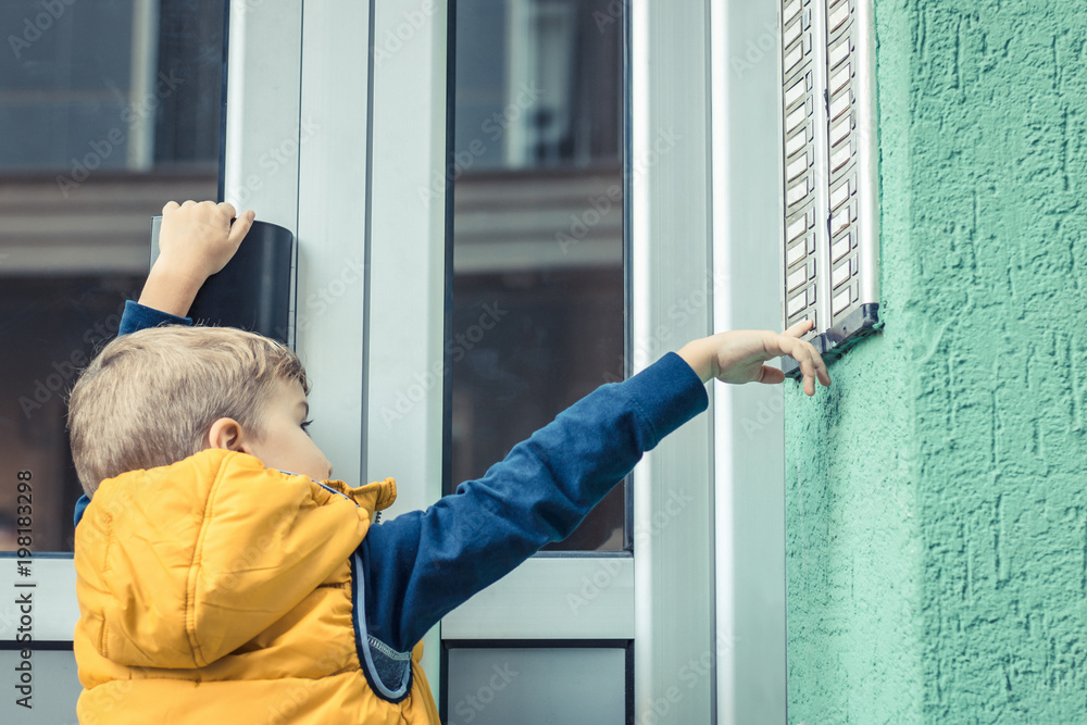 Little boy using intercom at building entrance Little boy using intercom at building entrance