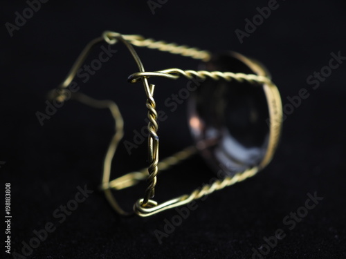 Muselet (wire from the cork)  from bottle of champagne. Isolated on black background. Selective focus. Macro
