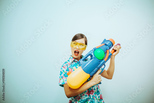 Young beautiful woman holding Songkran thailand festival with gun water colorful on white and blue background.