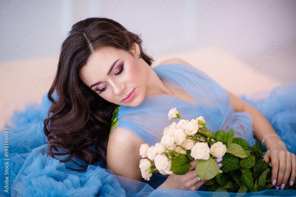 beautiful girl with dark hair with flowers in her hands in a blue dress beautiful girl with dark hair with flowers in her hands in a blue dress