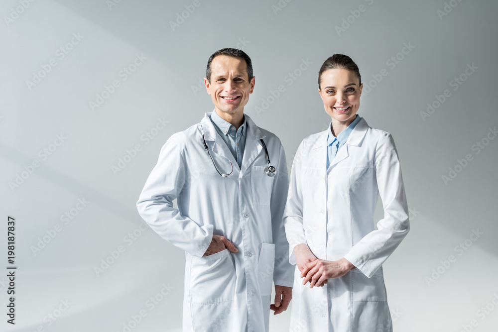 smiling adult doctors looking at camera on grey smiling adult doctors looking at camera on grey