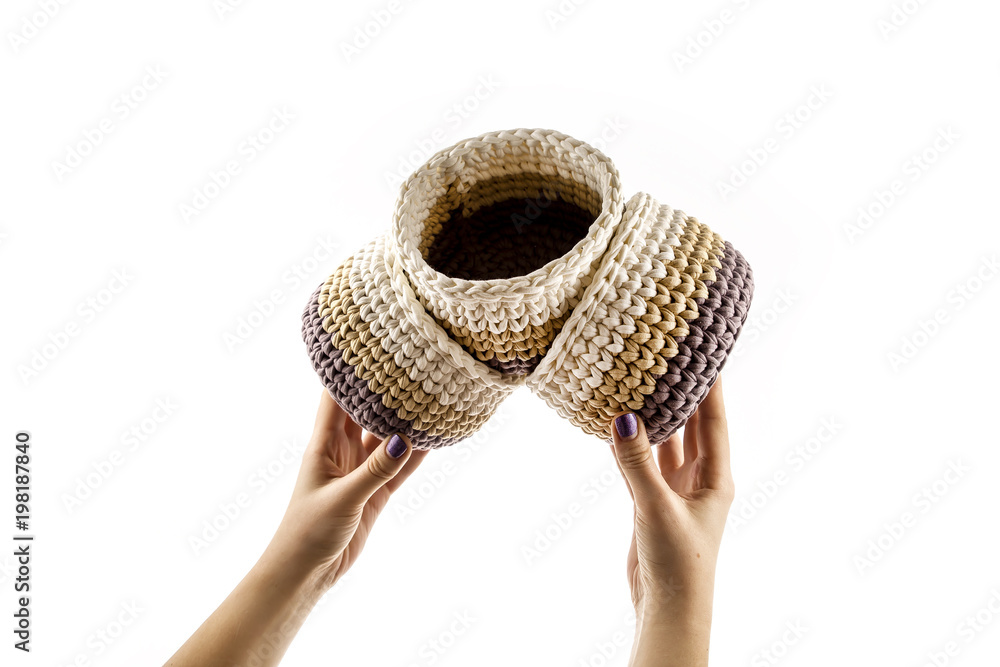 Fototapeta premium Woman's hand is holding a set of colorful crocheted baskets isolated on white background.