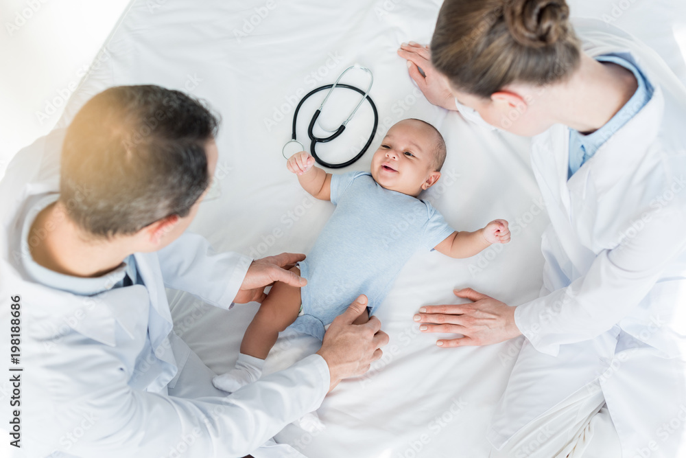 high angle view of pediatricians playing with little baby on bed