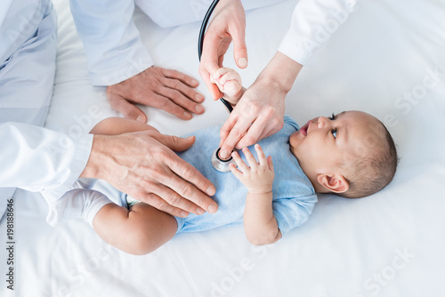 cropped shot of pediatricians listening heartbeat of little baby with stethoscope