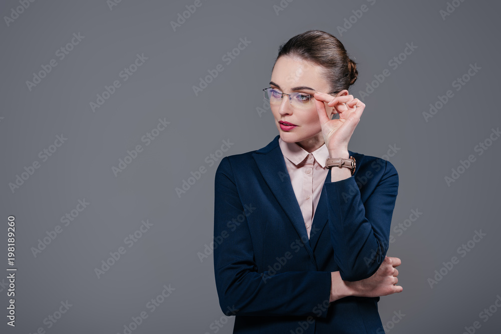 beautiful adult businesswoman in stylish suit and eyeglasses looking away isolated on grey beautiful adult businesswoman in stylish suit and eyeglasses looking away isolated on grey