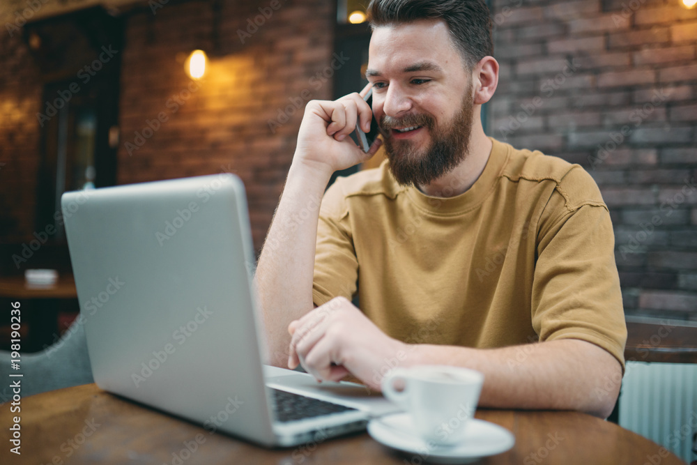 Man using laptop and smart phone while sitting in cafe. New technologies concept Man using laptop and smart phone while sitting in cafe. New technologies concept