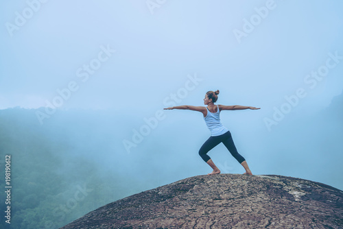 Asian women relax in the holiday. Travel relax. Play if yoga. On the Moutain rock cliff. Nature of mountain forests in Thailand
