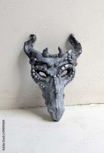 Dragon mask standing by a white wall