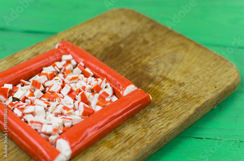 Crab sticks on cutting board on rustic wooden tableon a light green wooden background. photo