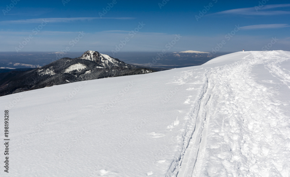 Trampled path in the snow by hikers and traces of skiers on the ridge in the mountains. Trampled path in the snow by hikers and traces of skiers on the ridge in the mountains.