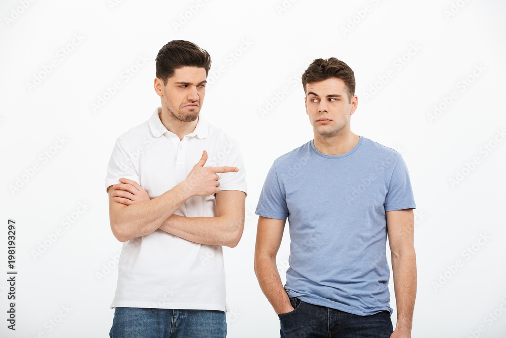 Portrait of two disappointed young men pointing finger Portrait of two disappointed young men pointing finger