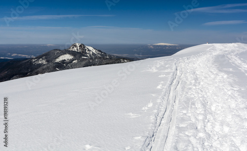 Trampled path in the snow by hikers and traces of skiers on the ridge in the mountains.