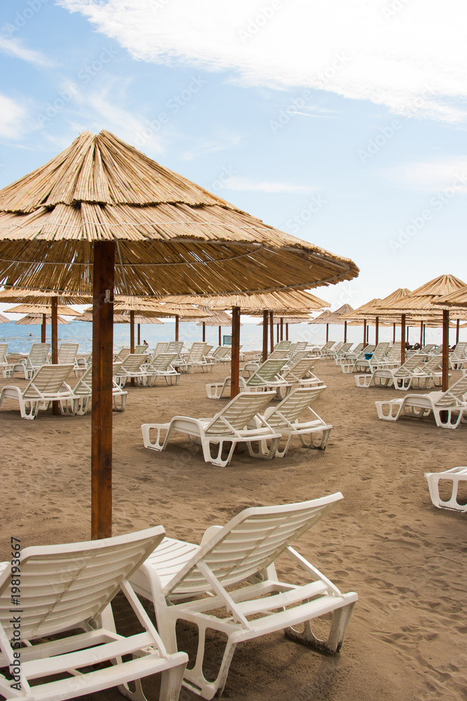 Beautiful empty beach with rows of sun beds under straw umbrellas