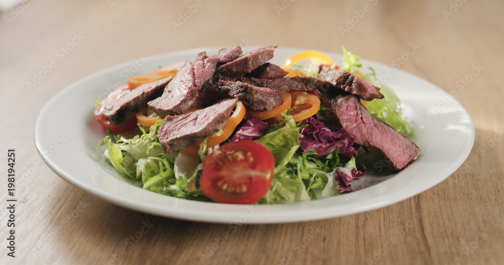 adding fillet mignon steak into salad