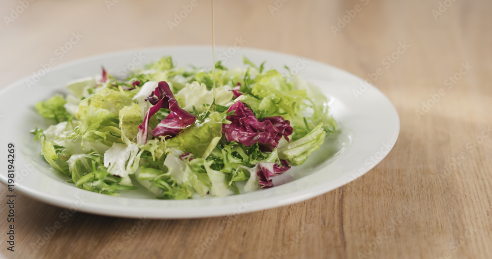 adding olive oil to salad leaves adding olive oil to salad leaves