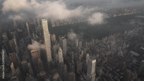 New York City aerial view flying over Midtown Manhattan skyscrapers toward Central Park at sunrise, with fog and low level clouds at sunrise. photo