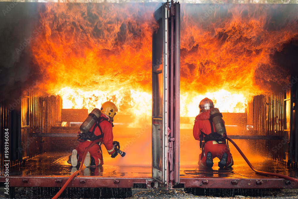 Fototapeta premium Firefighters training, Team practice to fighting with fire in emergency situation..Spray water to the flame in closed location