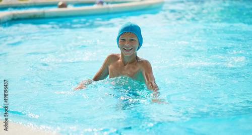 Teenager in an outdoor pool with a water slide.