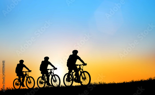 Silhouette man and bike relaxing on blurry sunrise background