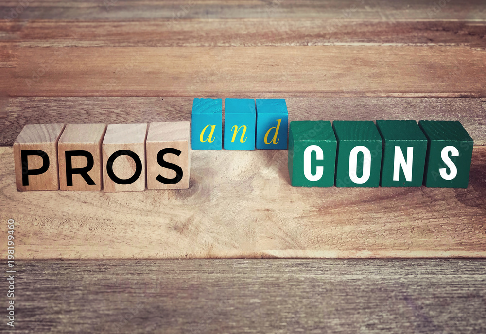 Fototapeta premium Conceptual - ‘PROS and CONS’ written on wooden blocks on a wooden table.